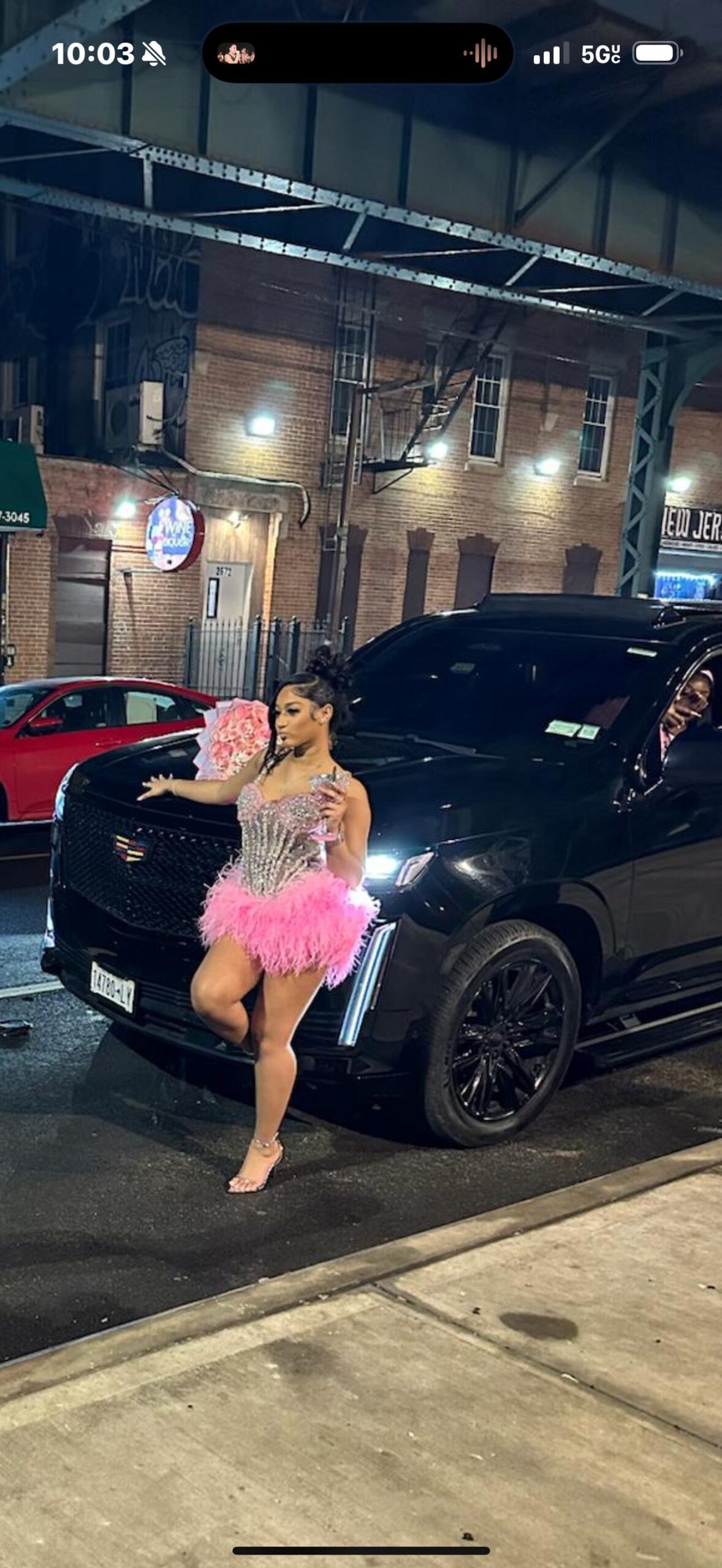 Luxury black SUV driving through Manhattan skyline at night with city lights reflecting on vehicle