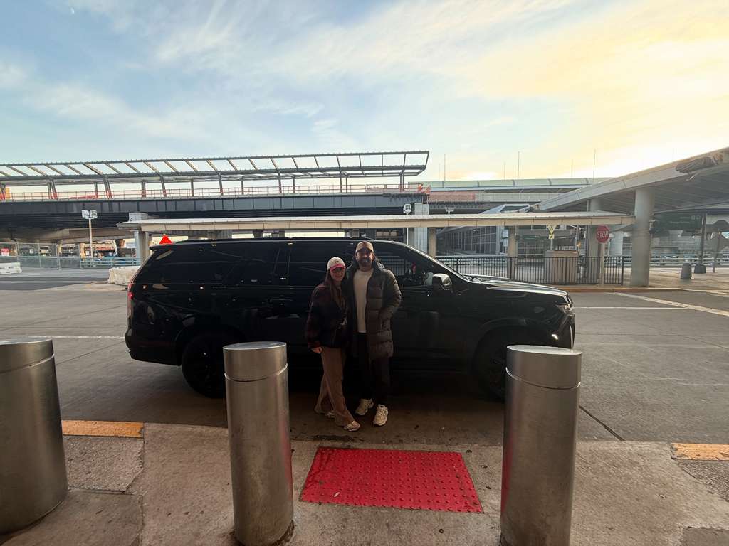 Professional chauffeur in black suit opening the door of a luxury black SUV for VIP client in Manhattan