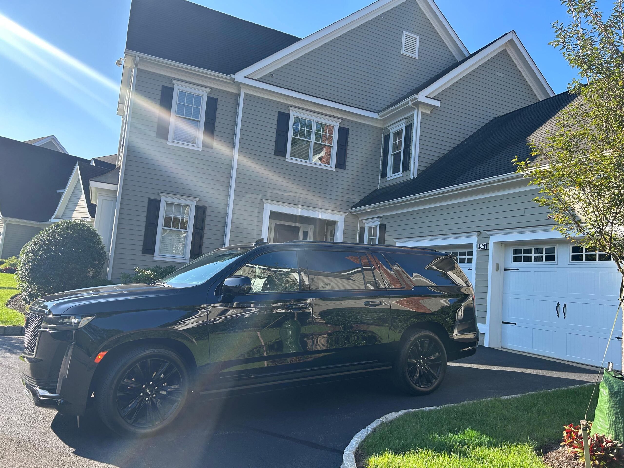 Professional chauffeur in black suit opening the door of a luxury black SUV for VIP client in Manhattan