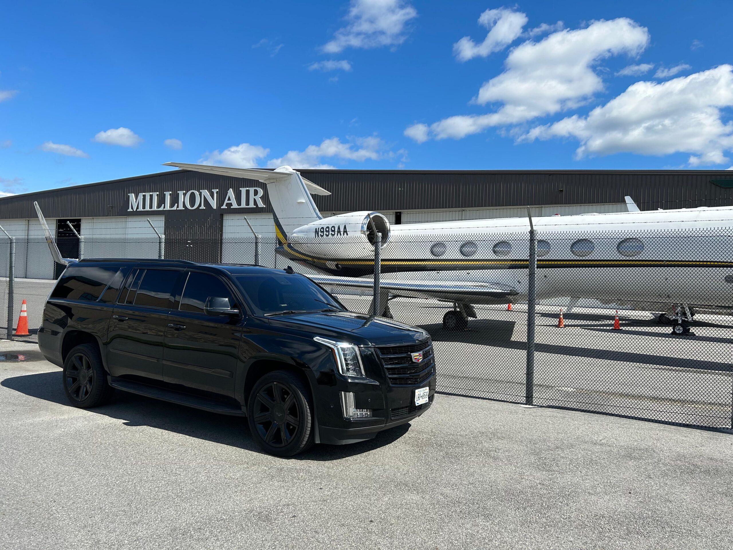 Professional chauffeur in black suit opening the door of a luxury black SUV for VIP client in Manhattan