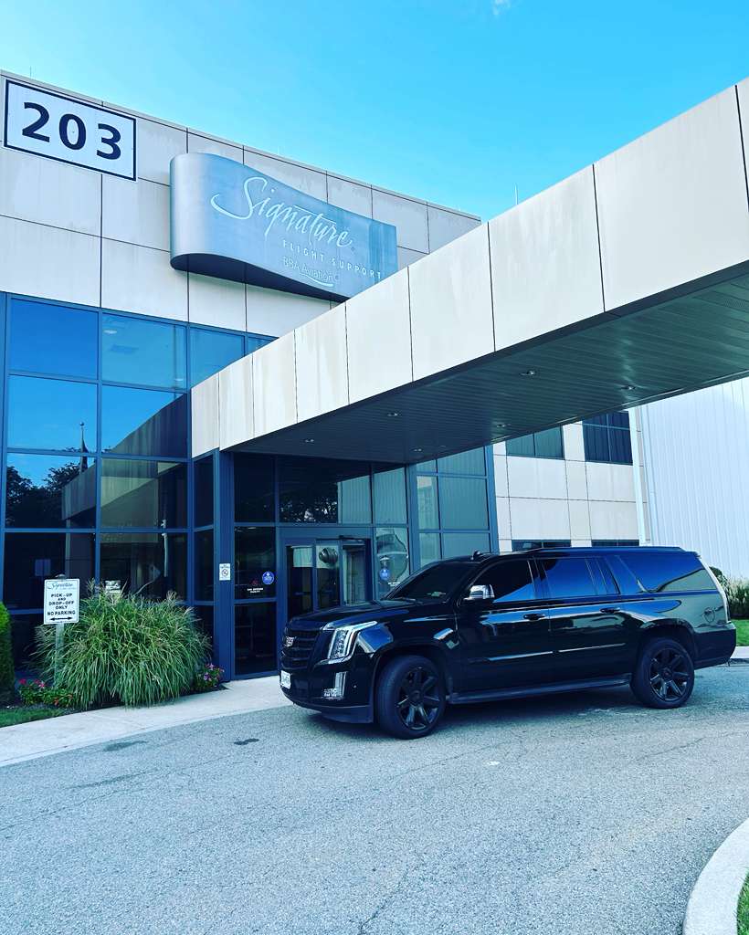 Professional chauffeur in black suit opening the door of a luxury black SUV for VIP client in Manhattan