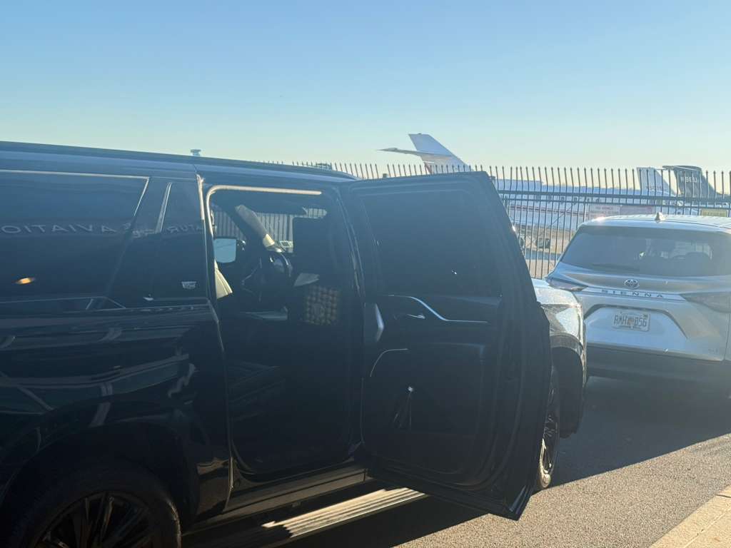 Professional chauffeur in black suit opening the door of a luxury black SUV for VIP client in Manhattan